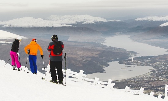 Three skiers taking in the view from the top of the Goose T-bar at Nevis Range, with Loch Eil in the distance