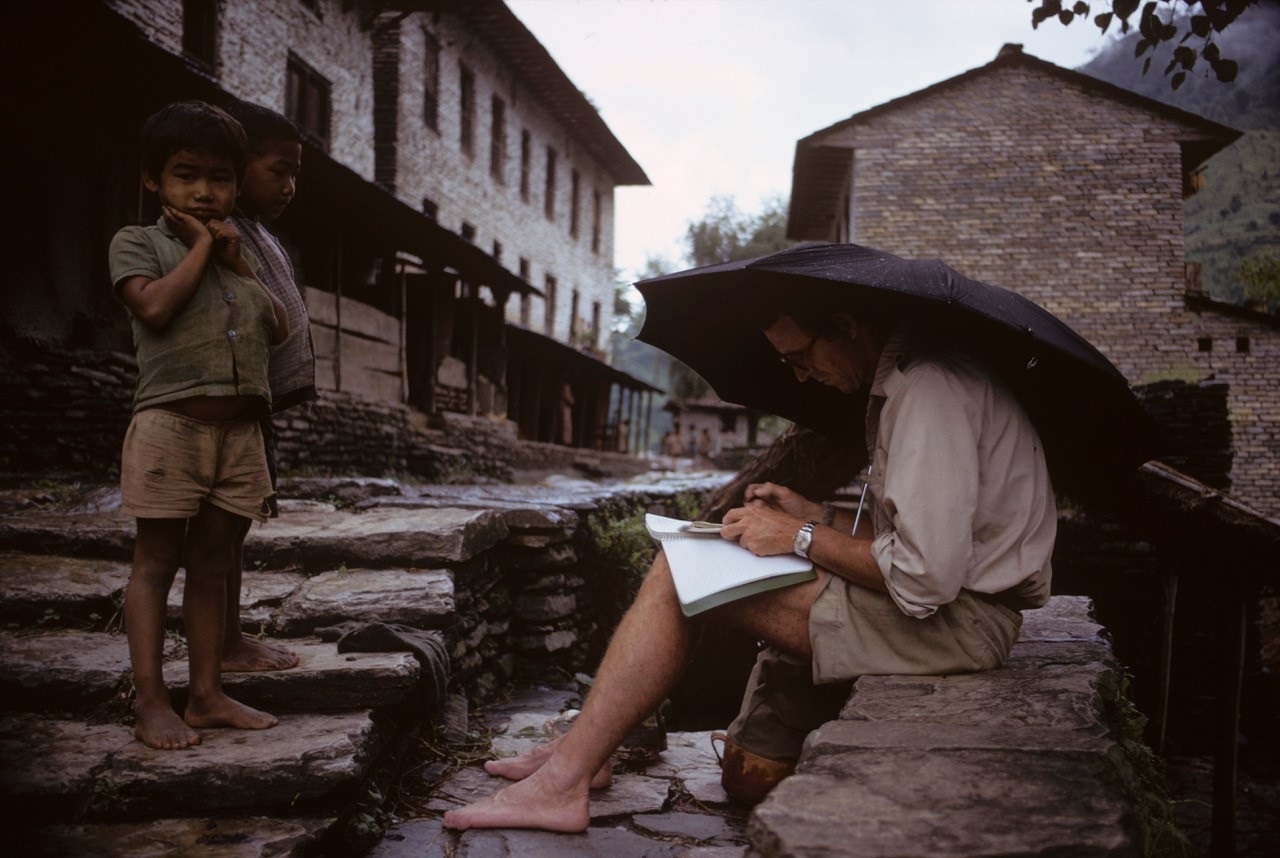 Peter Matthiessen taking notes during a break on the journey, watched by local children (Photo: George Schaller)