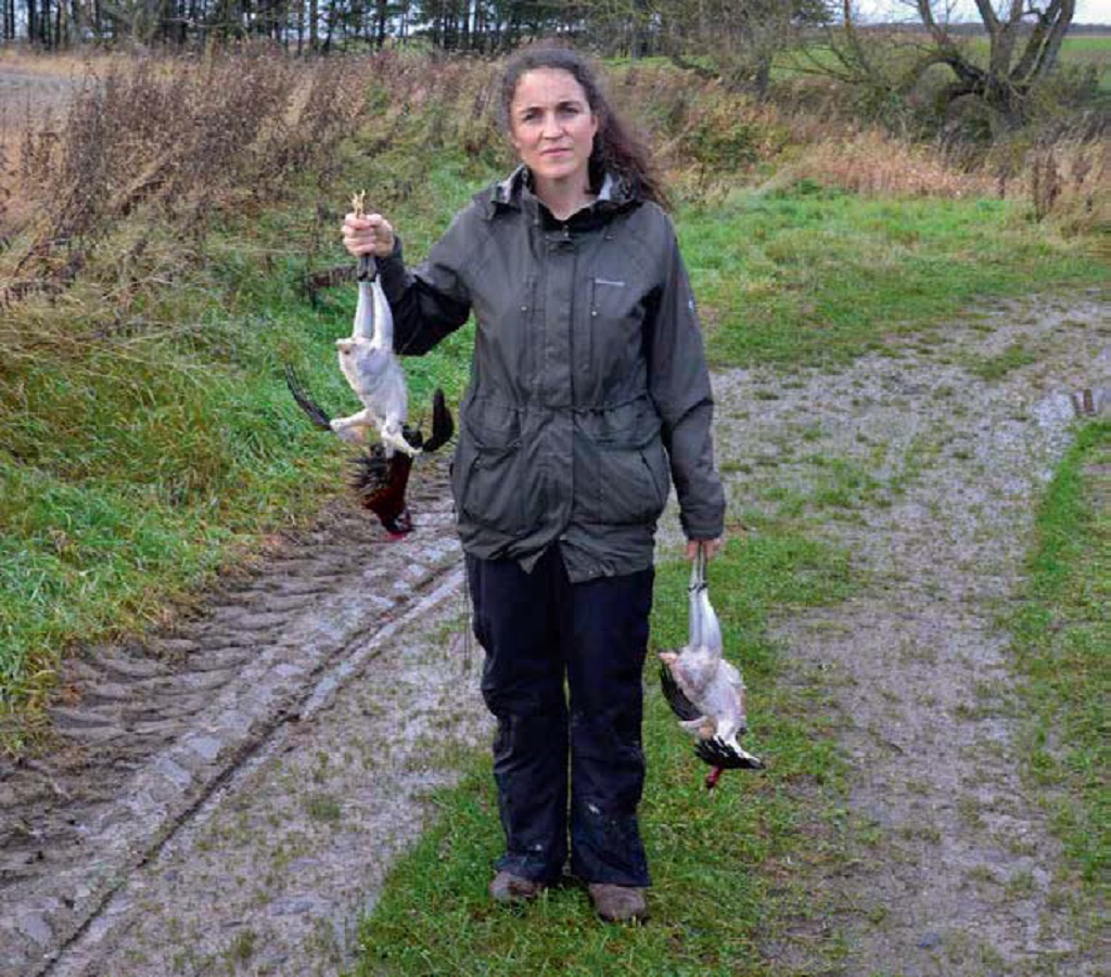 Louise Gray holds two roosters that have been killed and plucked by hand