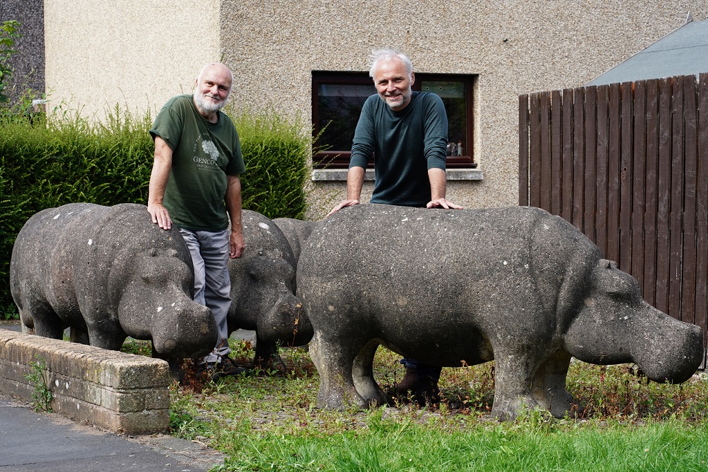 Programme Name: Meet You at the Hippos - TX: 30/11/2021 - Episode: Meet You at the Hippos (No. n/a) - Picture Shows: Stan and Mark Bonnar in Glenrothes with concrete hippos made by Stan in the 1970s Stan and Mark Bonnar in Glenrothes with concrete hippos made by Stan in the 1970s - (C) BBC/Objective Media - Photographer: Objective Media