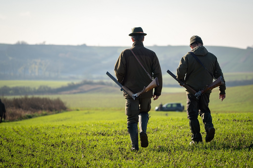 Couple,Of,Gamekeepers,Walk,Over,Cultivated,Field,Looking,For,A
