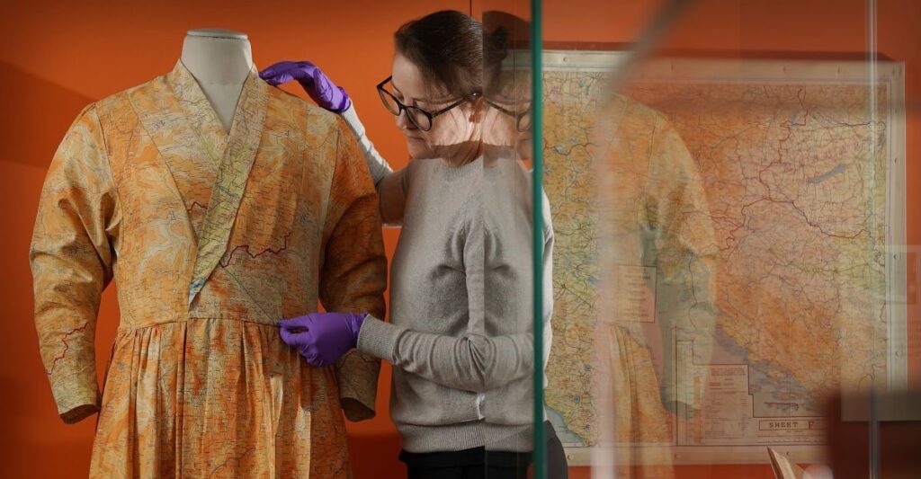 Stella Gardner adjusting a silk dress made from escape and evade maps. Credit: Stewart Attwood