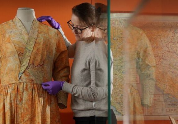 Stella Gardner adjusting a silk dress made from escape and evade maps. Credit: Stewart Attwood