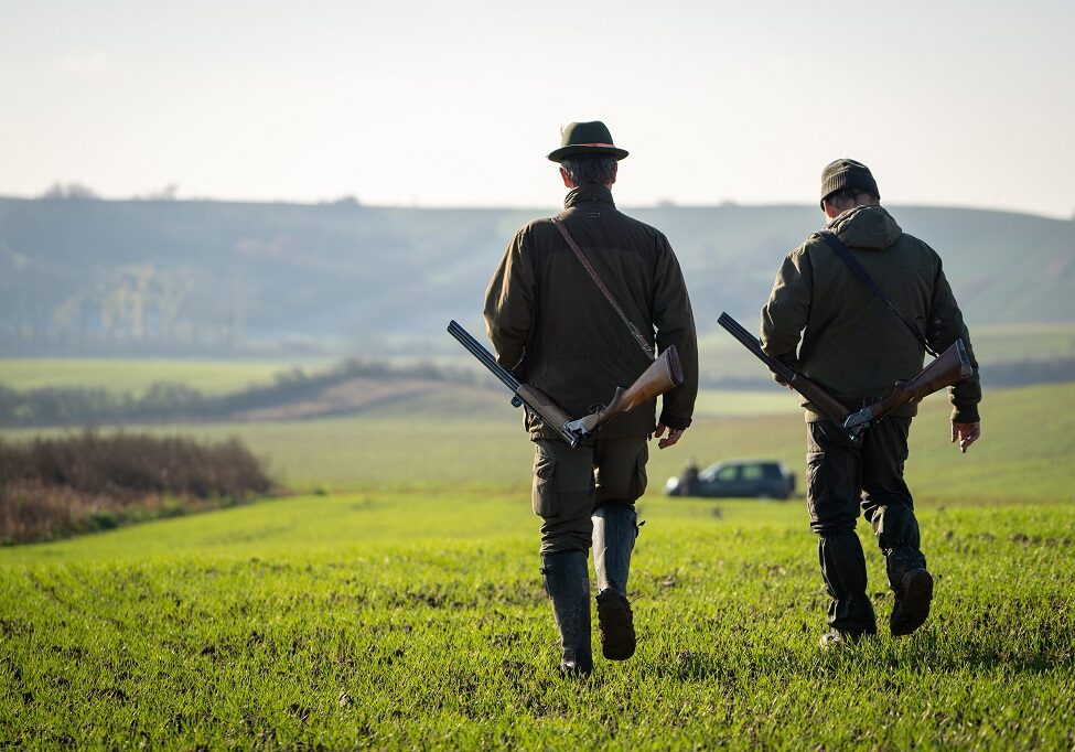 Couple,Of,Gamekeepers,Walk,Over,Cultivated,Field,Looking,For,A