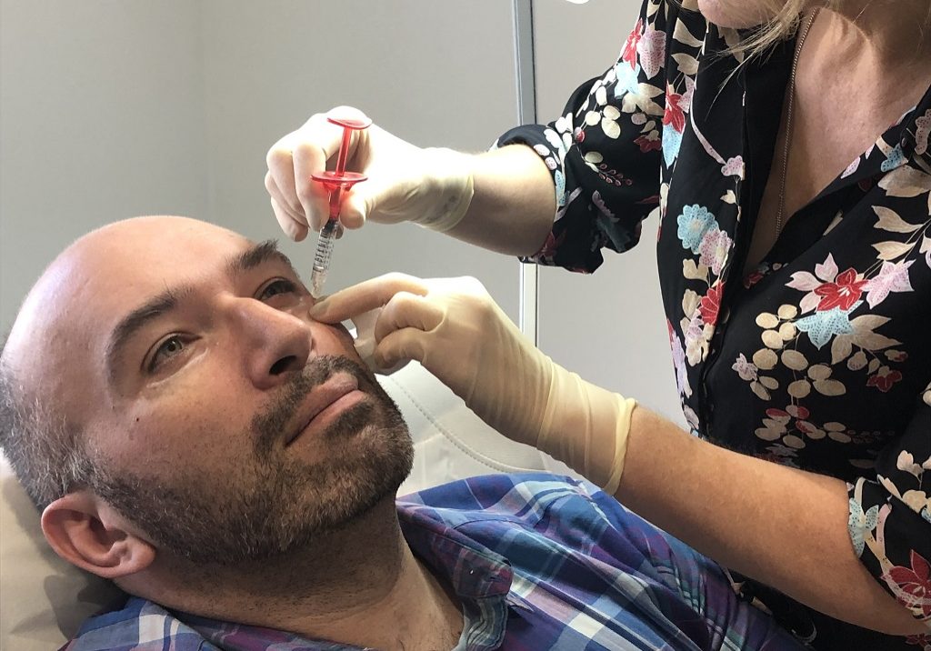 Dr Judy Todd administers an injection to Kenny Smith's face 