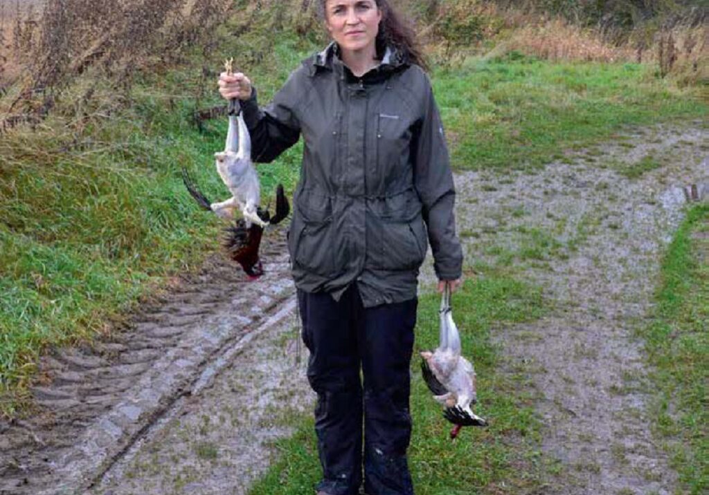 Louise Gray holds two roosters that have been killed and plucked by hand