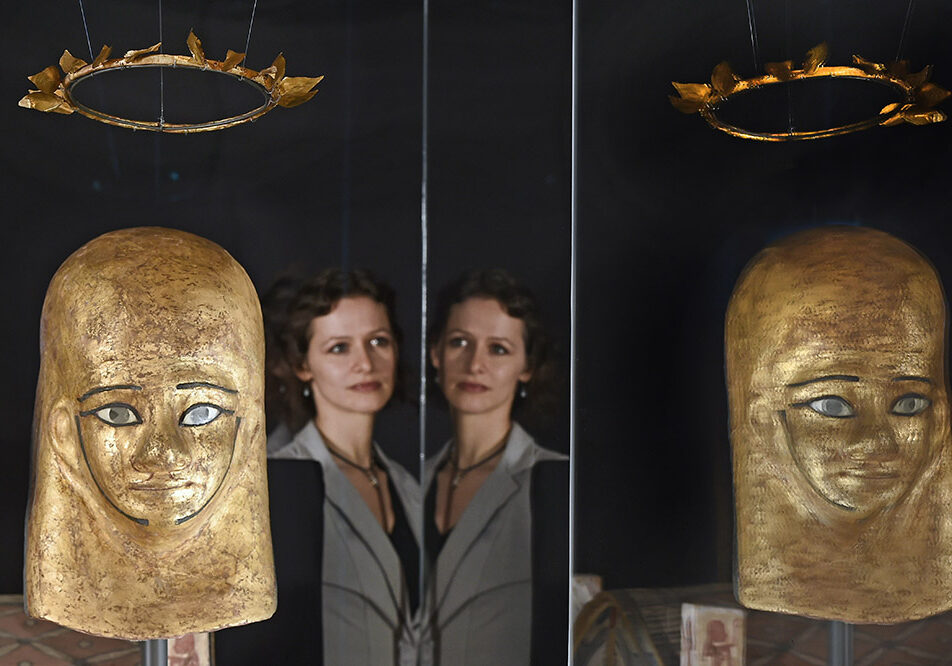 Assistant conservator Lydia Messerschmidt    views the mummy mask and wreath of Montsuef 
(Photo: Neil Hanna Photography)
