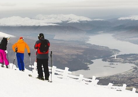 Three skiers taking in the view from the top of the Goose T-bar at Nevis Range, with Loch Eil in the distance